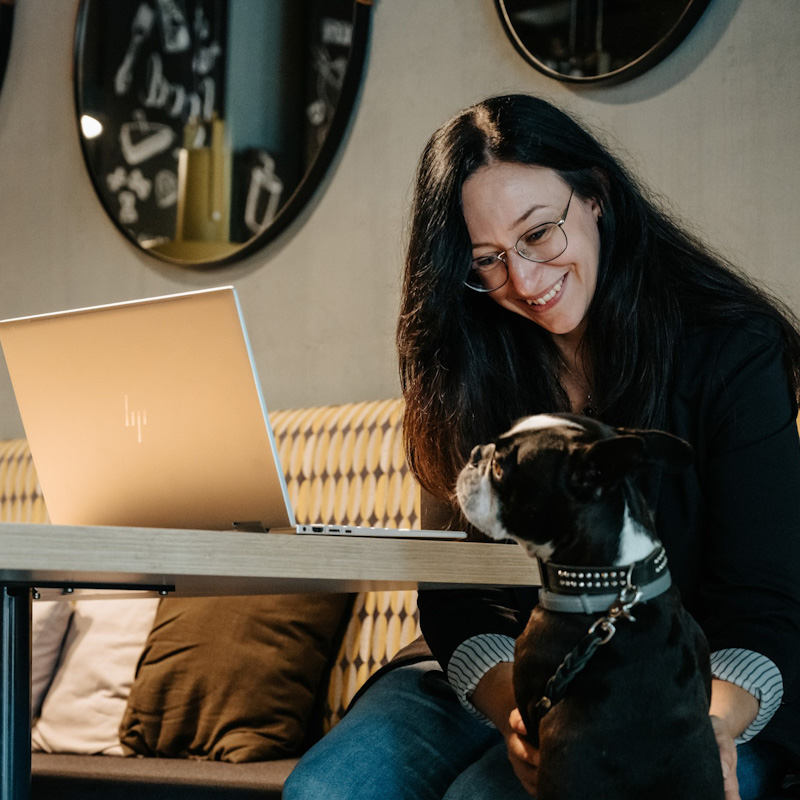 Tamara am Laptop, kleiner Hund schaut zu.